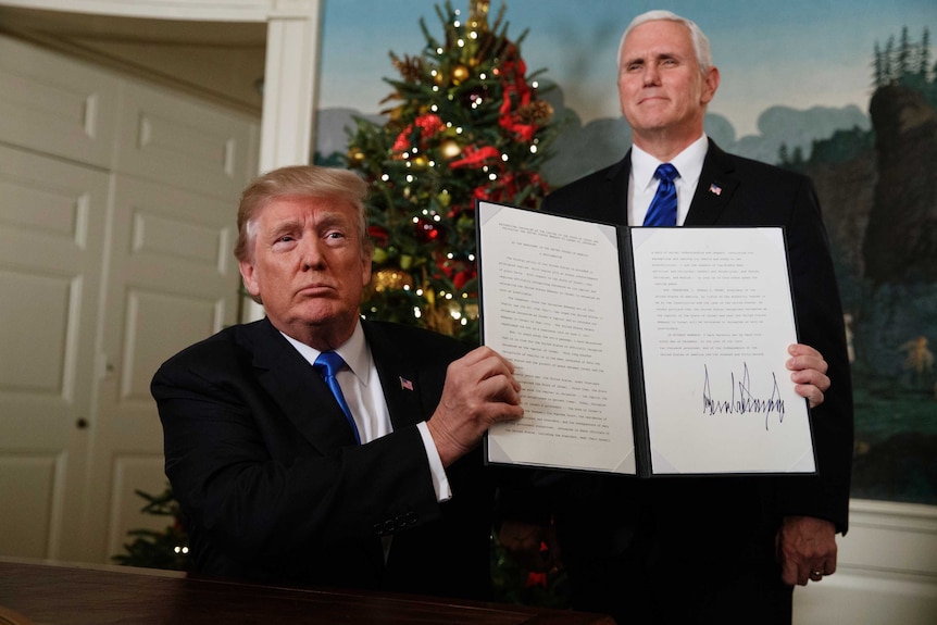 Mike Pence watches as Donald Trump holds up a proclamation recognising Jerusalem as the capital of Israel