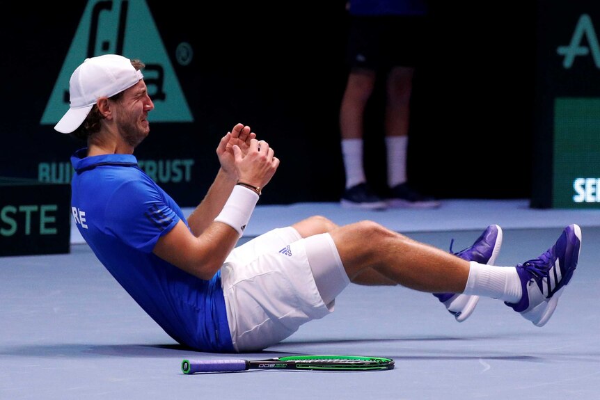 Lucas Pouille sits crying on the court celebrating winning the Davis Cup