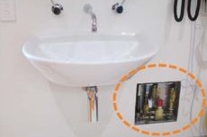 A white  bathroom-style basin on a wall inside the Perth Children's Hospital with a circled wall opening showing brass pipes.