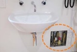 A white  bathroom-style basin on a wall inside the Perth Children's Hospital with a circled wall opening showing brass pipes.