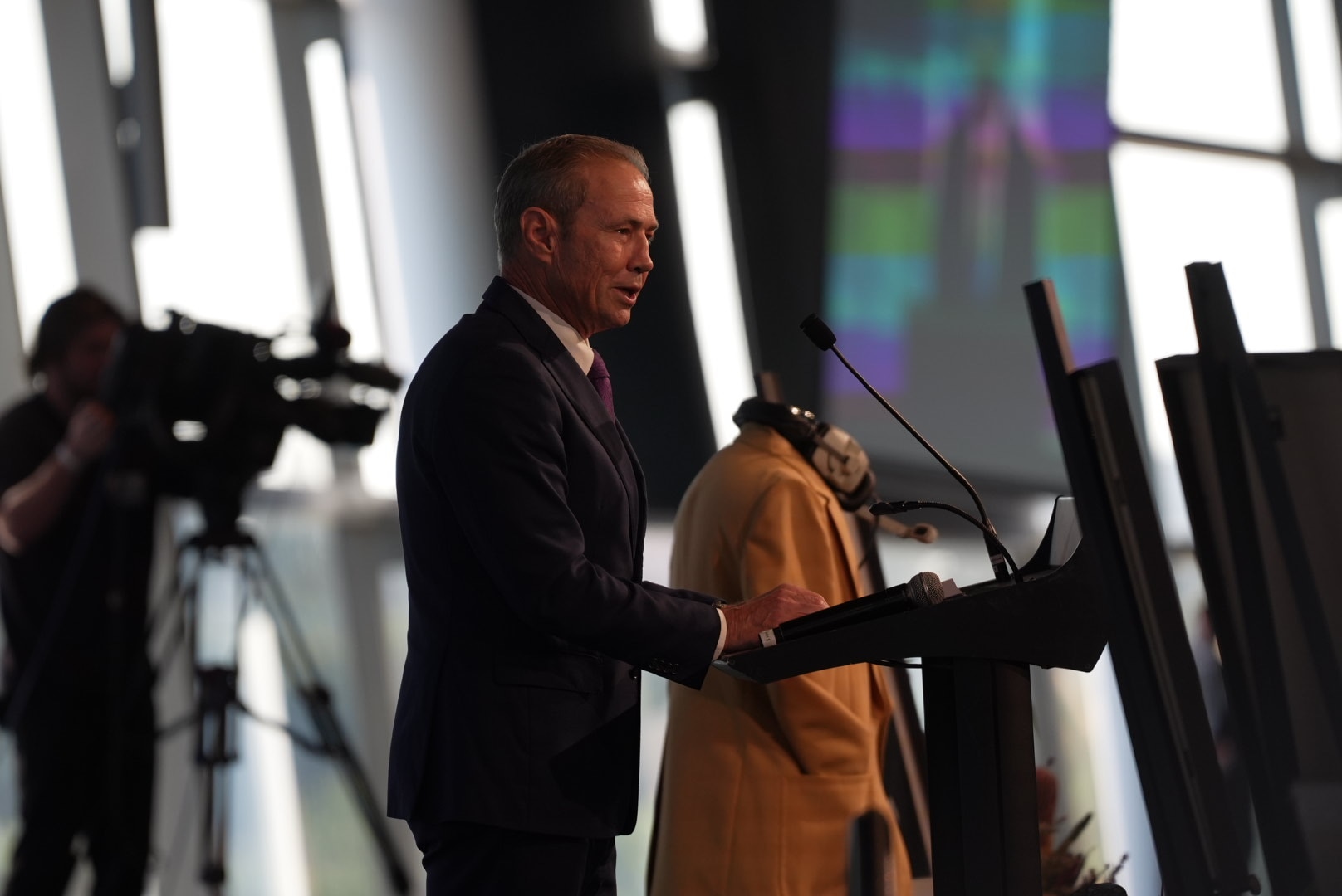 Roger Cook está falando atrás de um pódio. 