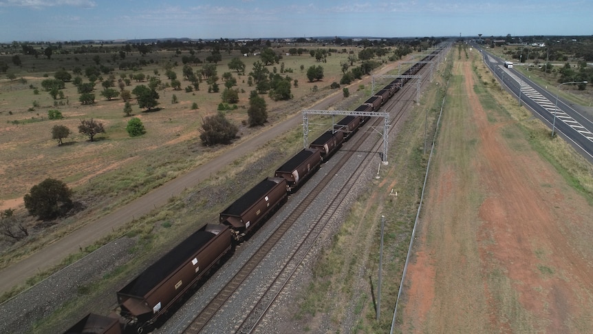 Birds eye view of a coal train in Queensland's Central Highlands. The grass surrounding the line is brown.  