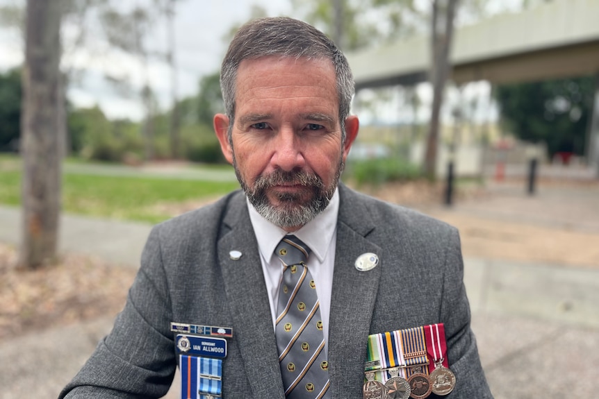 A man sitting at a table with war medals. 