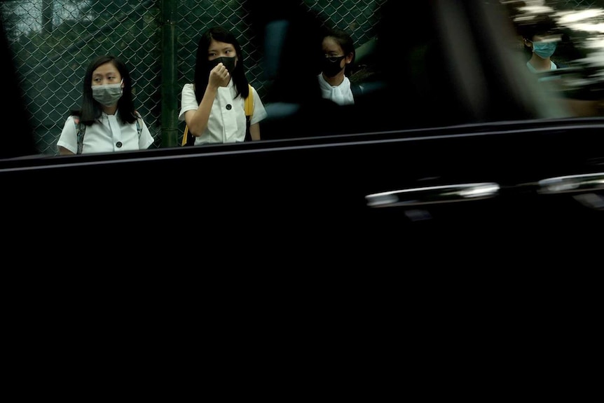 Maryknoll students in the human chain are seen in the reflection of a car window.