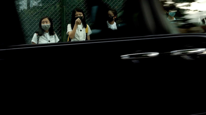 Maryknoll students in the human chain are seen in the reflection of a car window.