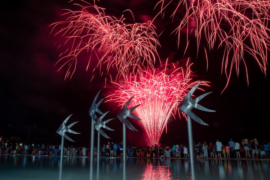 Bright red fireworks above pool in Cairns with iconic fish statues