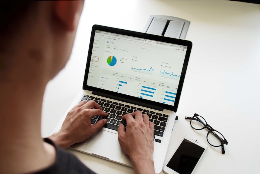 Woman typing on computer which displays graphs.