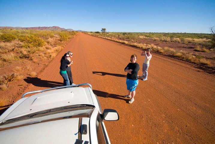Dr Skinner (in blue shorts) pictured with colleagues standing on a long red dirt road.