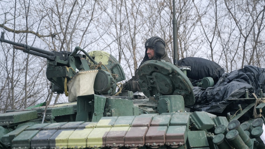 A service member of the Ukrainian armed forces is seen atop of a tank.