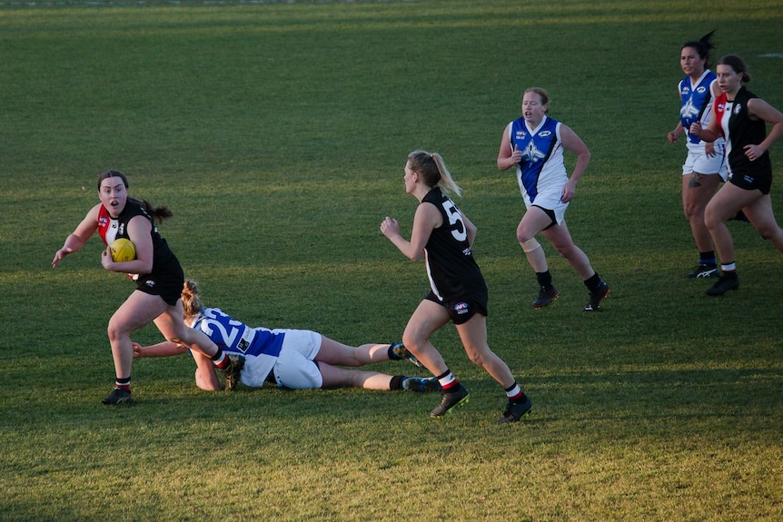 The Ainslie player takes the ball away while others chase after her.