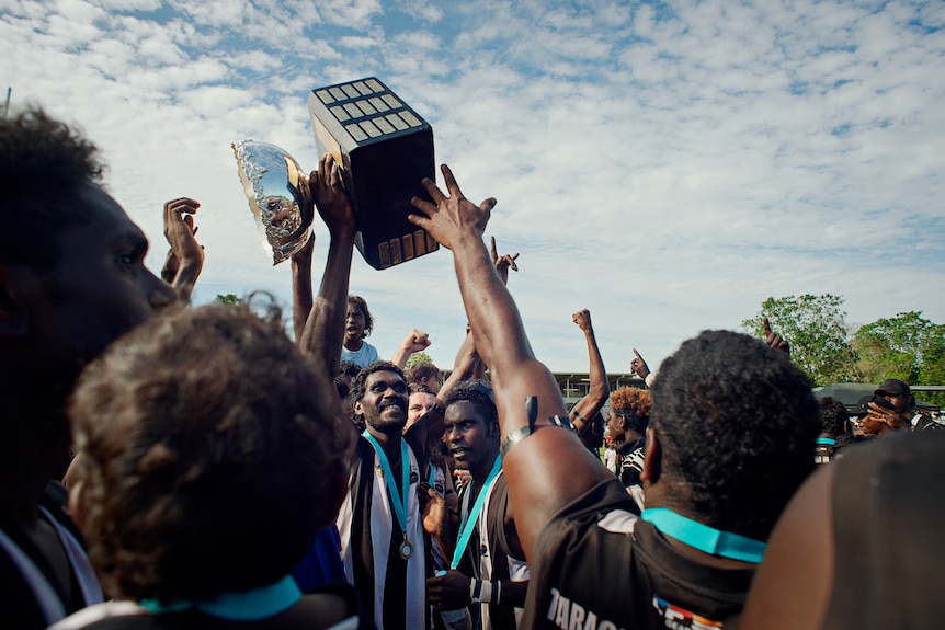footy players grab trophy