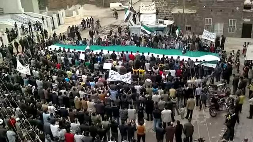 Image grab from YouTube shows anti-government protesters waving former Syrian flag.