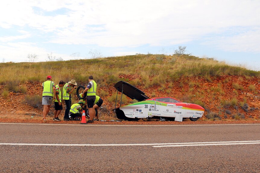 The TeamArrow car gets an emergency repair after a tyre puncture.