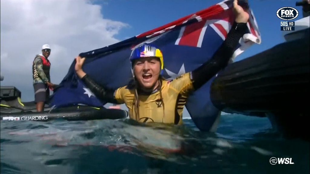 Molly Picklum drapes herself in an Australian flag while submerged in the ocean, celebrating her surfing win.