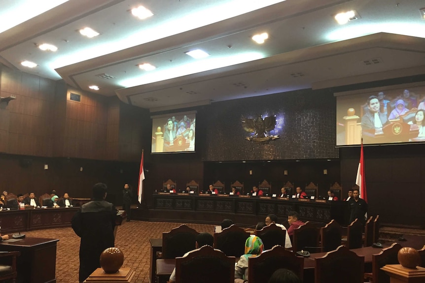 A view of Indonesia's Constitutional Court, with a lawyer talking at a stand.