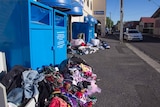 Clothing dumped on the ground next to charity bins