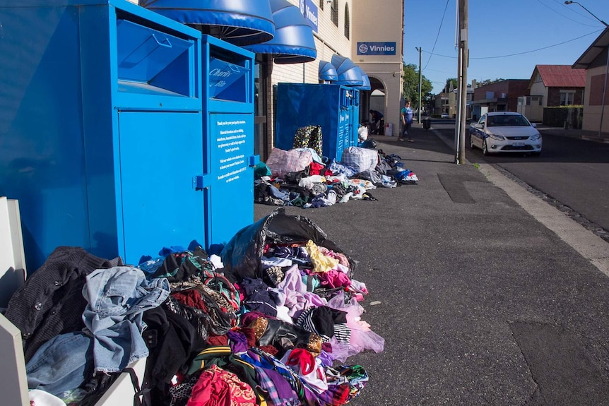 Clothing dumped on the ground next to charity bins