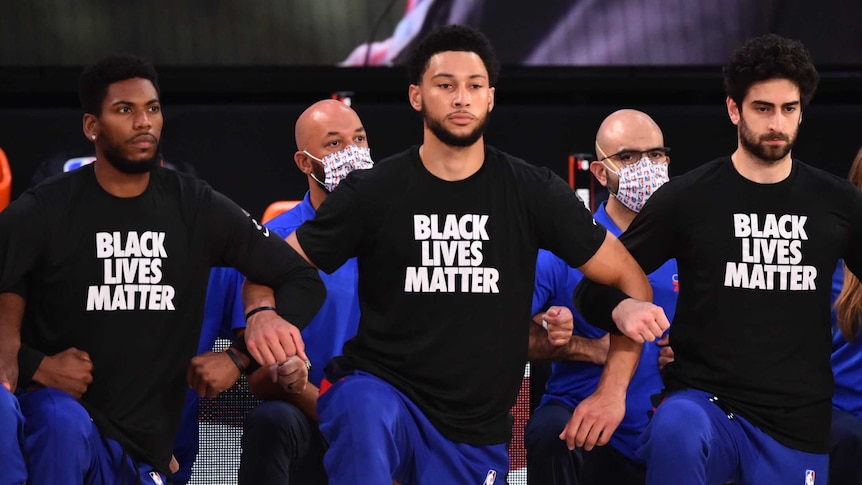 Members of the Philadephia 76ers basketball team wearing black lives matter tshirts take a new on the courts.