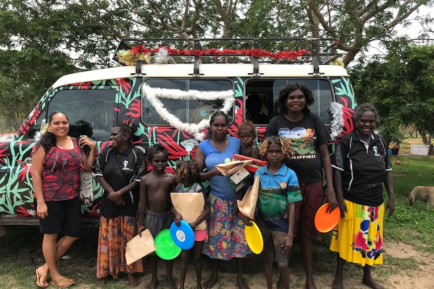 Women stand holding frisbees