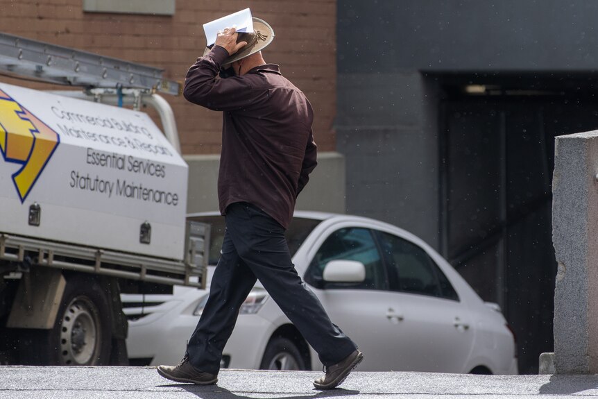 A man leaving court covering his face