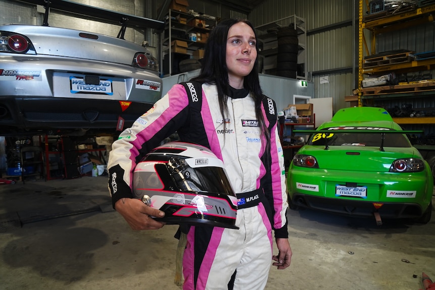 Motor sport driver Maisie Place in her race suit in her garage in Moruya. 