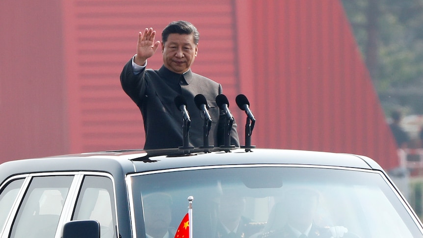 Președintele chinez Xi Jinping face semn cu mâna de pe trapa unei mașini în timp ce se adresează unei parade militare în China.