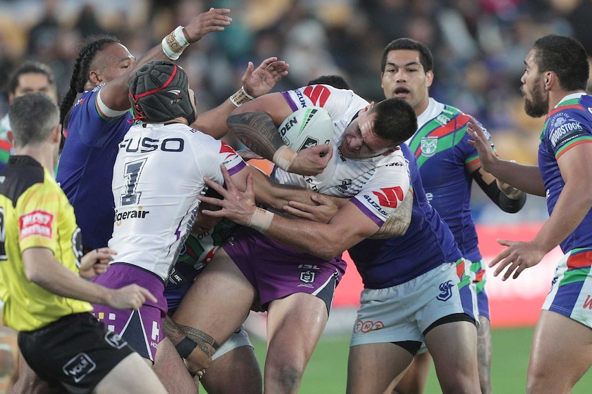 Nelson Asofa Solomona ducks his head while four Warriors players surround him and attempt to tackle him.