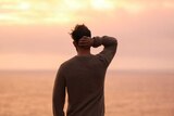 A man looks out over a body of water.