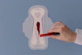 Red liquid is poured onto a period pad showing its absorbency in a TV advertisement.