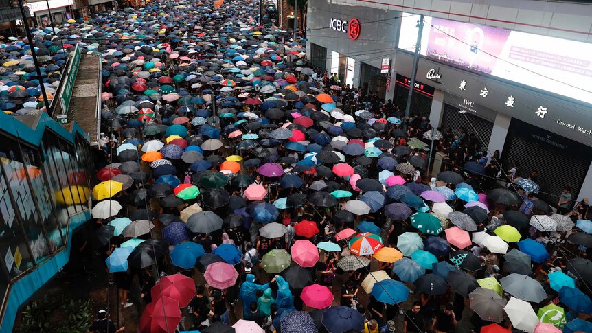 A bird's eye view of people marching through Hong Kong with colourful umbrellas