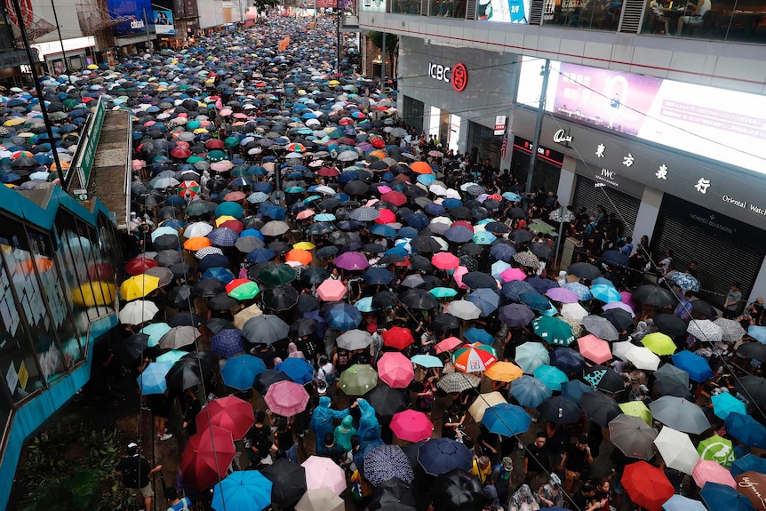 A bird's eye view of people marching through Hong Kong with colourful umbrellas