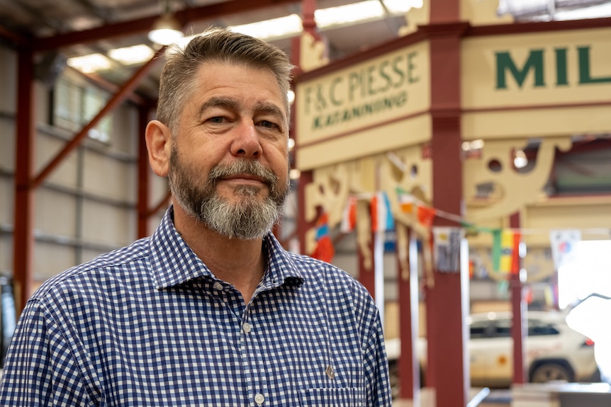 A middle-aged bearded man wearing a plaid shirt 