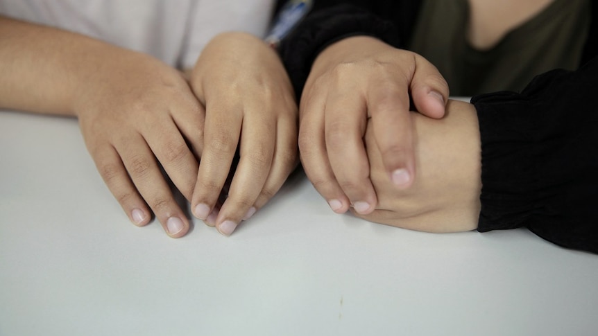 A close up shot of the hands of two young Saudi sisters