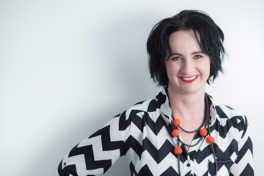 Woman wearing a black and white shirt smiles at the camera.