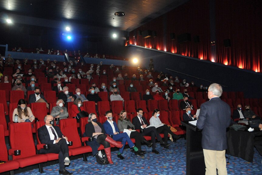 A crowd sits in a cinema auditorium