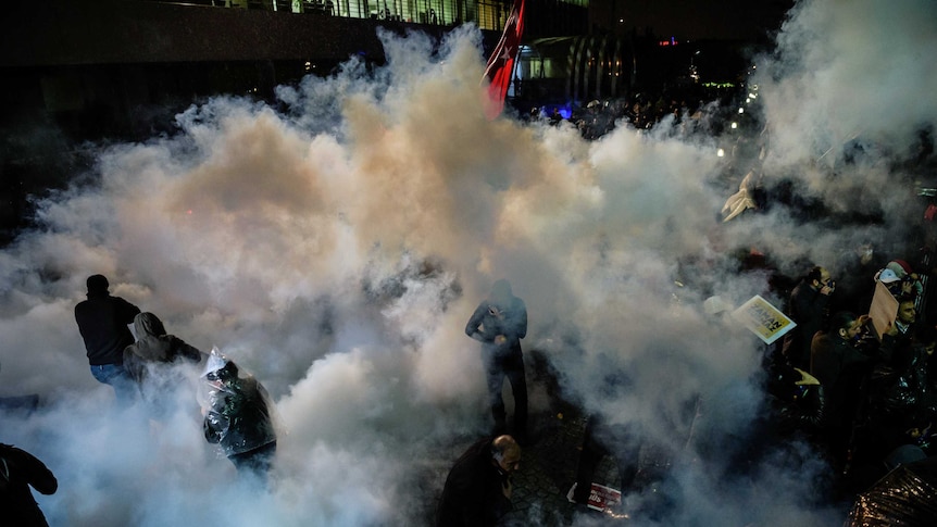 Turkish anti riot police officers launch water cannon and tear gas to disperse supporters of the Turkish Zaman Daily newspaper