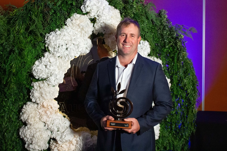 A man holds up an award