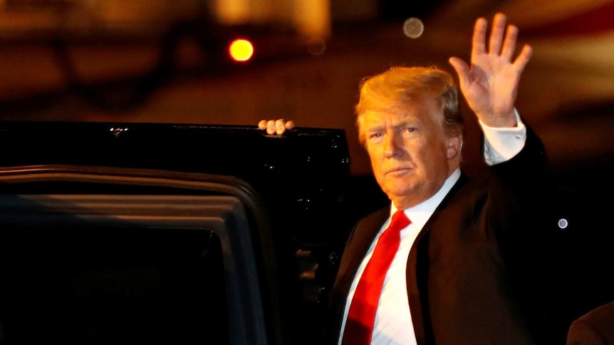 Donald Trump waves as he gets into a car.