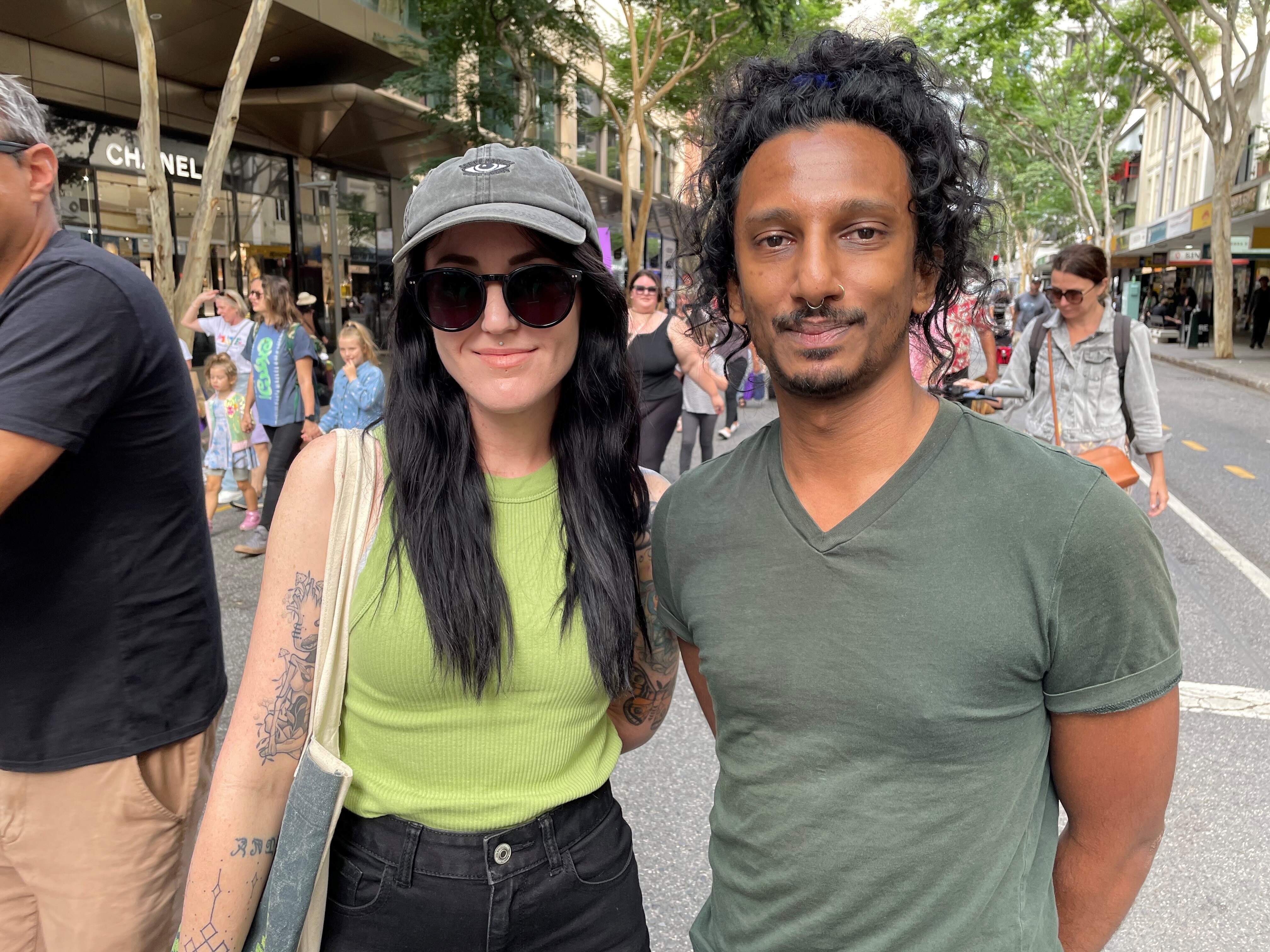 A woman and man stand side by side in the middle of a city street.