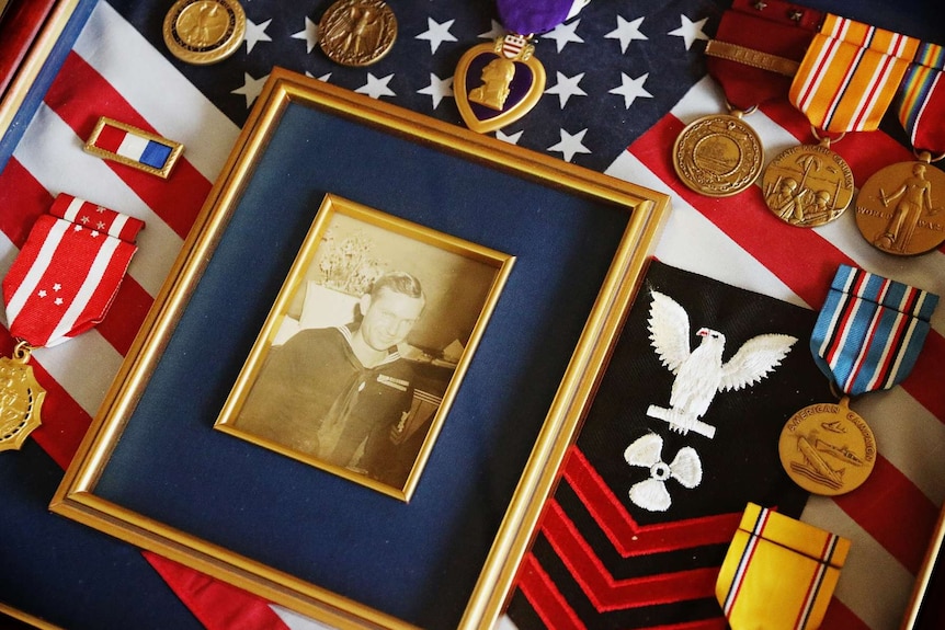 A photograph of a young Samuel Logan in service on top of a US flag.