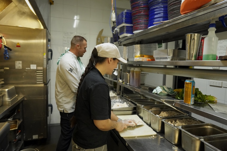 A commercial kitchen with two people cooking.