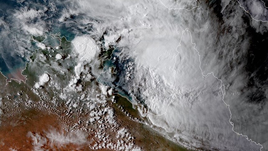 Cyclone Trevor is seen from a birds' eye view as white cloud off the coast of NT. The land next to it is green and orange desert
