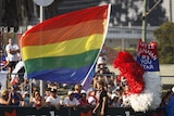 A rainbow flag waves on the sidelines.