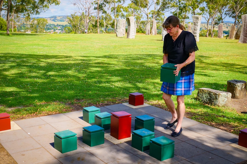 A woman moves a piece on a giant outdoor Celtic game like chess