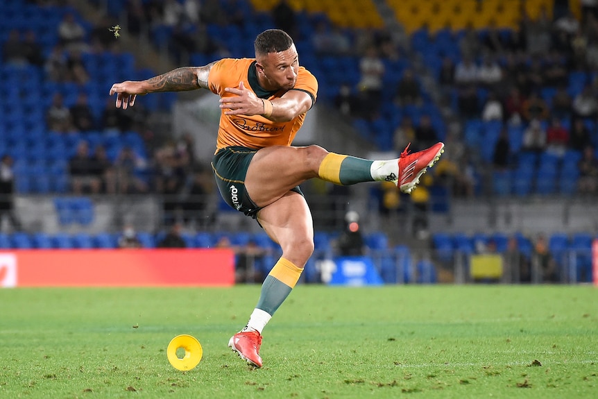 An Australian rugby union player swings his leg through after kicking a penalty goal, as the tee lies on the ground.