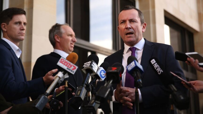 Mr McGowan speaks into a nest of microphones in front of Parliament House.