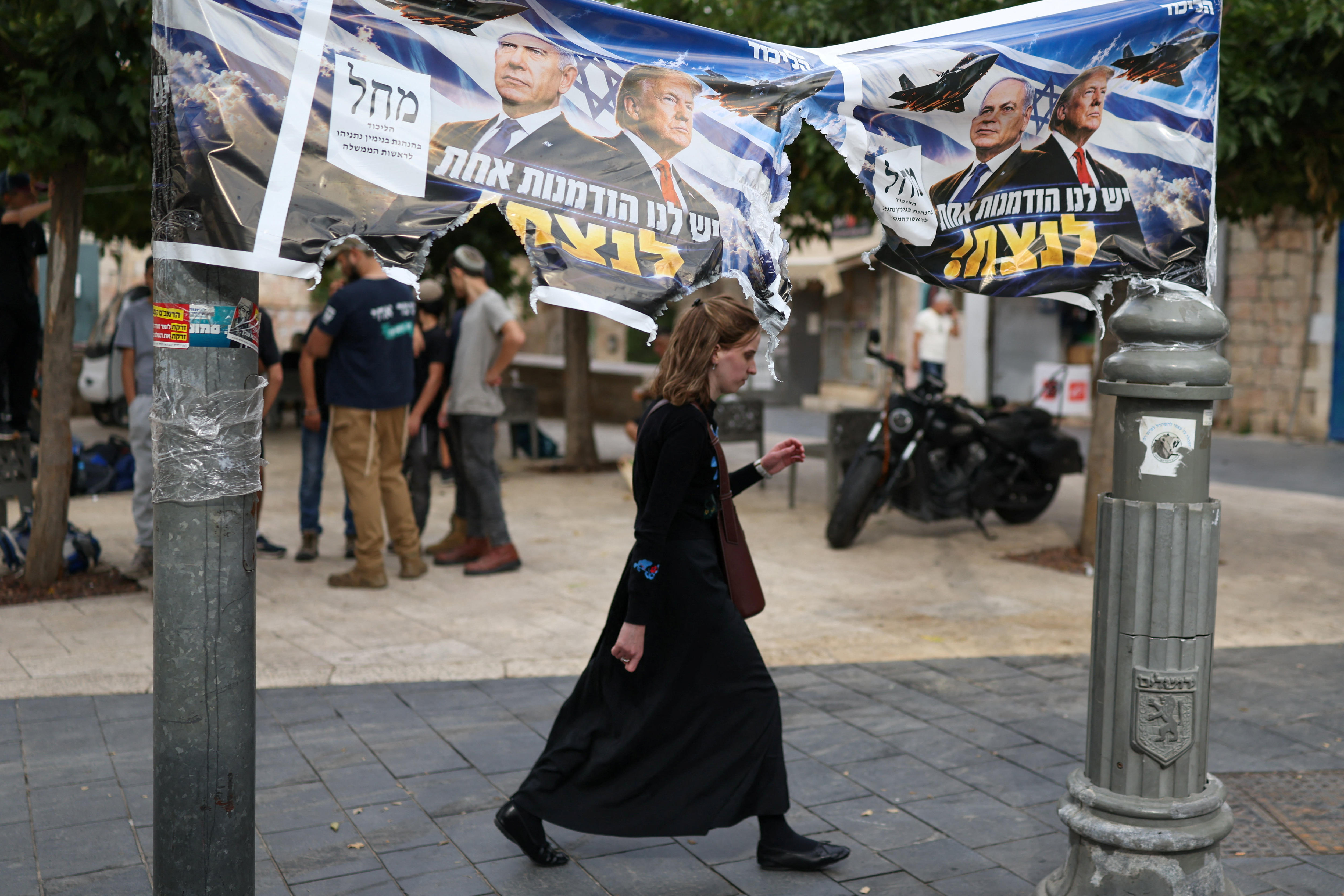 A woman passes by a banner depicting Israeli Prime Minister Benjamin Netanyahu and US President Donald Trump.