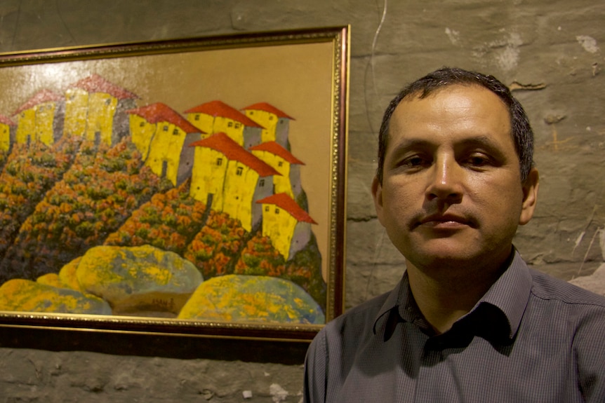 Crimean Tatar Erfan Kudosov-Beshuili stands next to a painting in his art gallery.