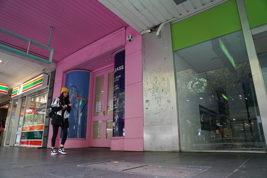 A woman walks past empty shops in Melbourne's CBD.