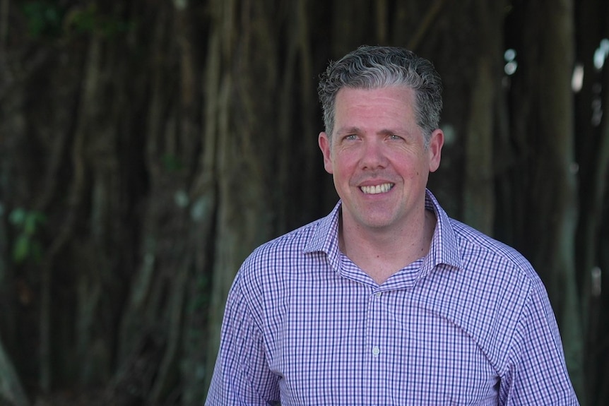 Mark Olsen from Tropical Tourism North Queensland smiling with trees behind him